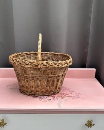 Brocante rieten mand van warm bruin riet met hengsel. Ideaal als marktmand, opbergmand of decoratief woonaccessoire in een landelijk of vintage interieur.